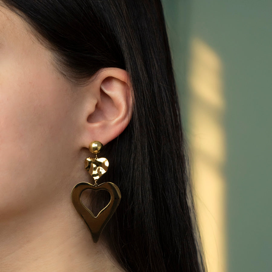 Goudkleurige oorbellen in hartvorm gedragen door model