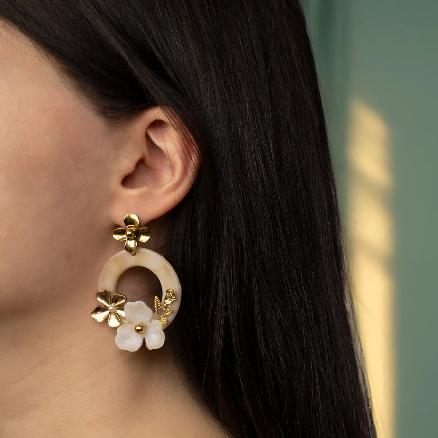 Oorbellen met bloemen, in de kleur goud gedragen door model